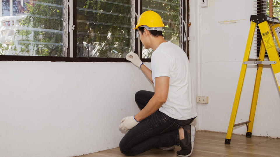 A man working on window blinds inside a house