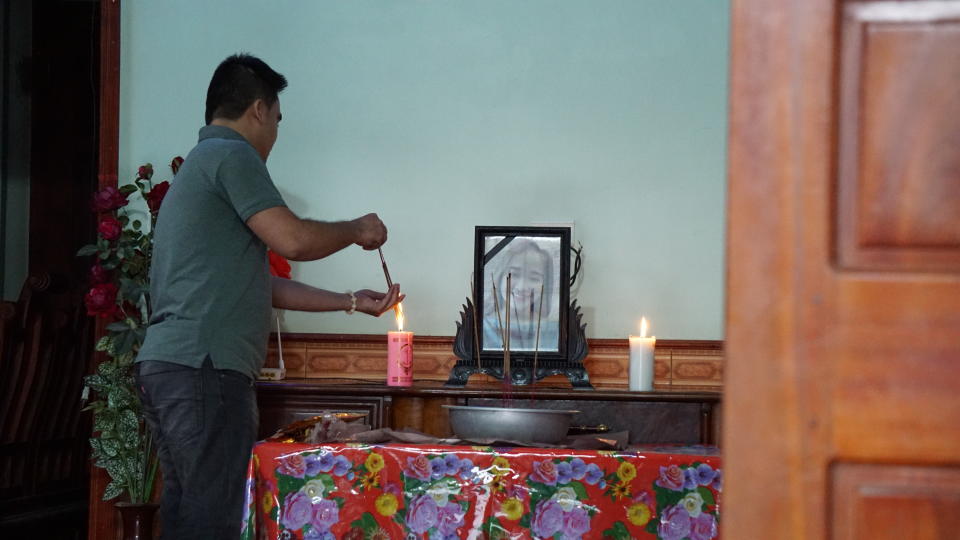 A family member of Bui Thi Nhung lights incense sticks from a candle at an altar with Nhung's portrait inside her home home Saturday, Oct. 26, 2019 in Do Thanh village, Nghe An province, Vietnam. Family members fear that Nhung could be among the dozens of people found dead in the back of a truck in England. (AP Photo/Linh Do)