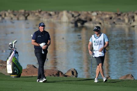 Jan 19, 2019; La Quinta, CA, USA; Phil Mickelson (left) reacts after his second shot on the on the 18th hole as caddie Tim Mickelson looks on during the third round of the Desert Classic golf tournament at PGA West - Stadium Course. Mandatory Credit: Orlando Ramirez-USA TODAY Sports