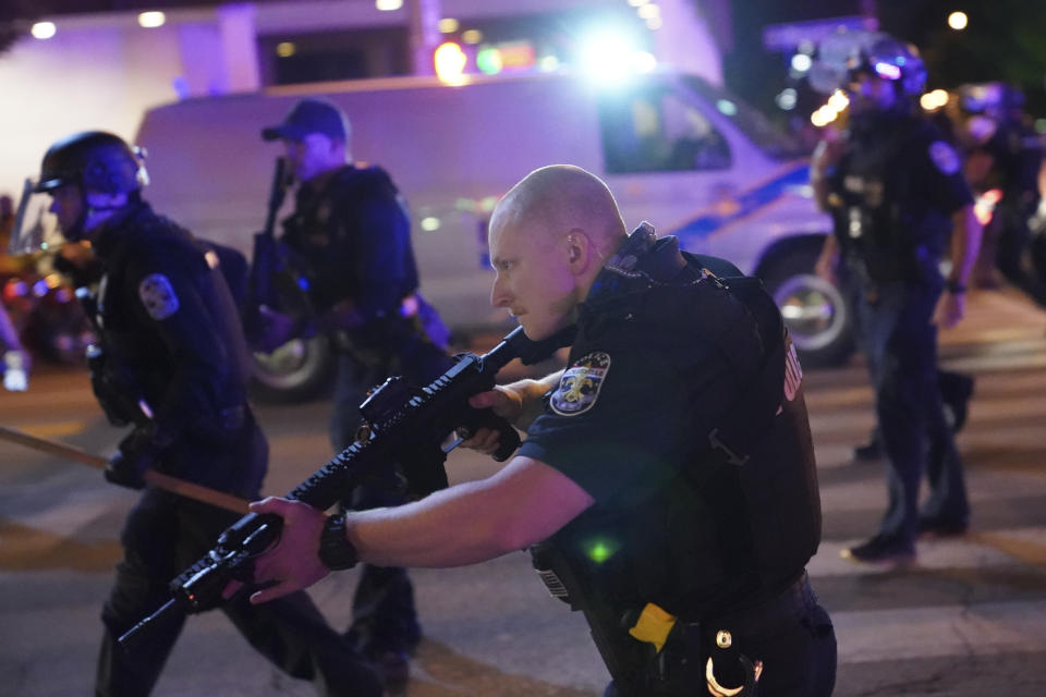 Police move after a Louisville Police officer was shot, Wednesday, Sept. 23, 2020, in Louisville, Ky. A grand jury has indicted one officer on criminal charges six months after Breonna Taylor was fatally shot by police in Kentucky. The jury presented its decision against fired officer Brett Hankison Wednesday to a judge in Louisville, where the shooting took place. (AP Photo/John Minchillo)