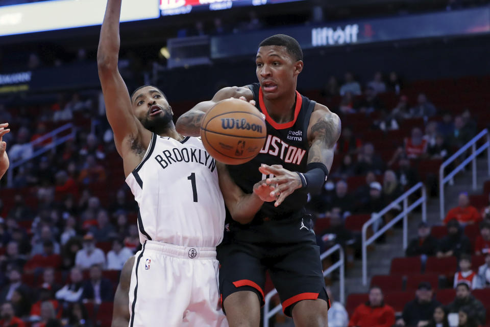 Houston Rockets forward Jabari Smith Jr., right, passes the ball around Brooklyn Nets forward Mikal Bridges (1) during the first half of an NBA basketball game Wednesday, Jan. 3, 2024, in Houston. (AP Photo/Michael Wyke)