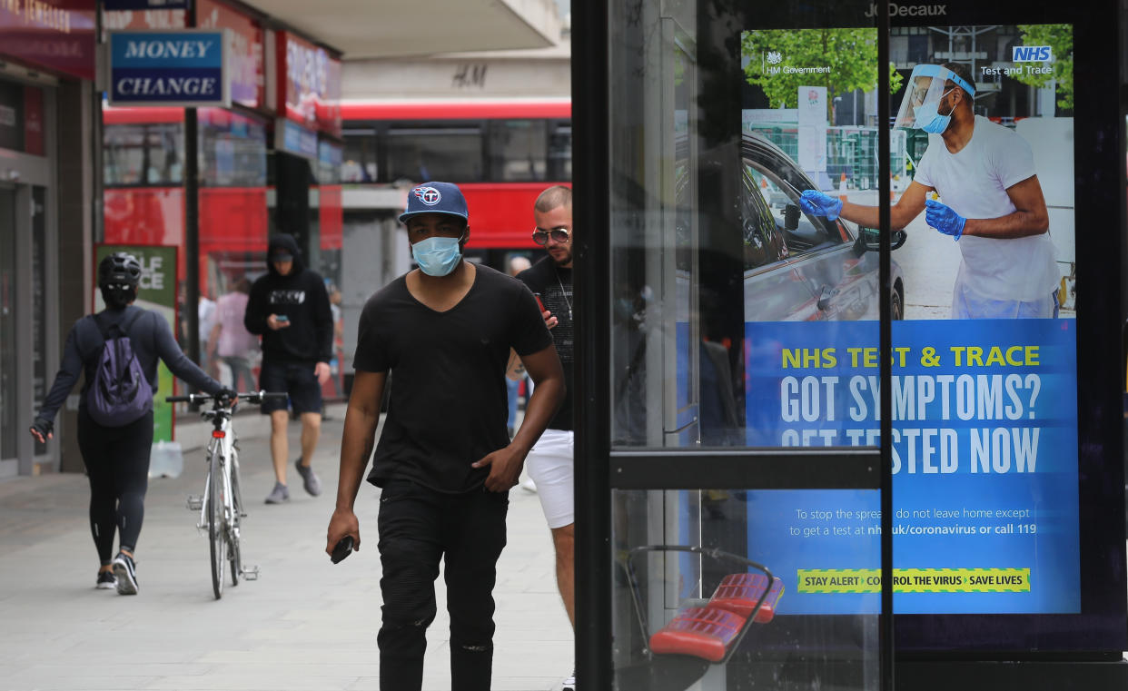 A pedestrian walks past a screen on a bus stop displaying a NHS notice on test and trace on Oxford Street, London, as non-essential shops in England open their doors to customers for the first time since coronavirus lockdown restrictions were imposed in March. Picture date: Monday June 15, 2020.