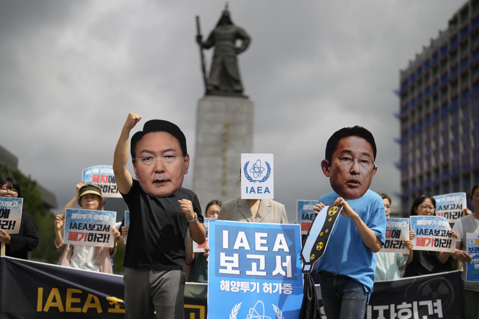 Members of civic groups wearing masks of Japanese Prime Minister Fumio Kishida, right, and South Korean President Yoon Suk Yeol pose during a rally to oppose Japanese government's decision to release treated radioactive water into the sea from the Fukushima nuclear power plant, in Seoul, South Korea, Wednesday, July 5, 2023. The letters read "Report of the IAEA." (AP Photo/Lee Jin-man)