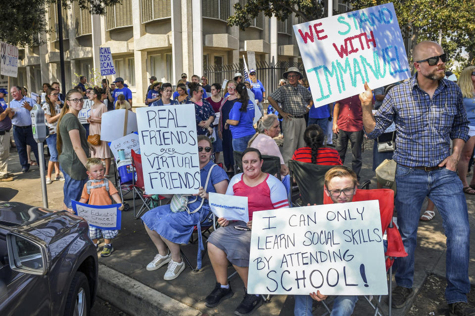 FILE - In this Aug. 25, 2020 file photo hundreds of Immanuel Schools supporters hold signs and gather outside the B.F. Sisk Courthouse in support of the schools' decision to defy the county's COVID-19 orders prior to a court hearing in Fresno, Calif. The California private school has been ordered to pay $15,000 for defying a judge's order to close classrooms and stop in-person teaching. The decision Tuesday, Oct. 20, 2020, in the Fresno County Superior Court ends a nearly three-month legal battle between Immanuel Schools, a private K-12 Christian school in California's Central Valley, and county and state officials. (Craig Kohlruss/The Fresno Bee via AP, File)