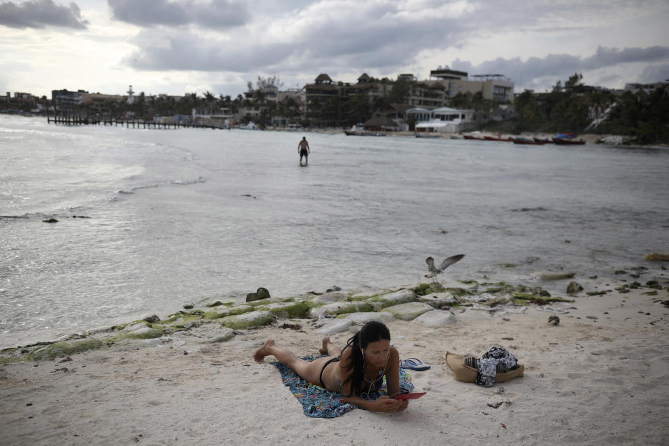 A tourist relaxes on the shore of Mamitas beach amid the new coronavirus pandemic in Playa del Carmen, Quintana Roo state, Mexico, Tuesday, Jan. 5, 2021. Concern is spreading that the winter holiday bump in tourism could be fleeting because it came as COVID-19 infections in both Mexico and the United States were reaching new heights. (AP Photo/Emilio Espejel)