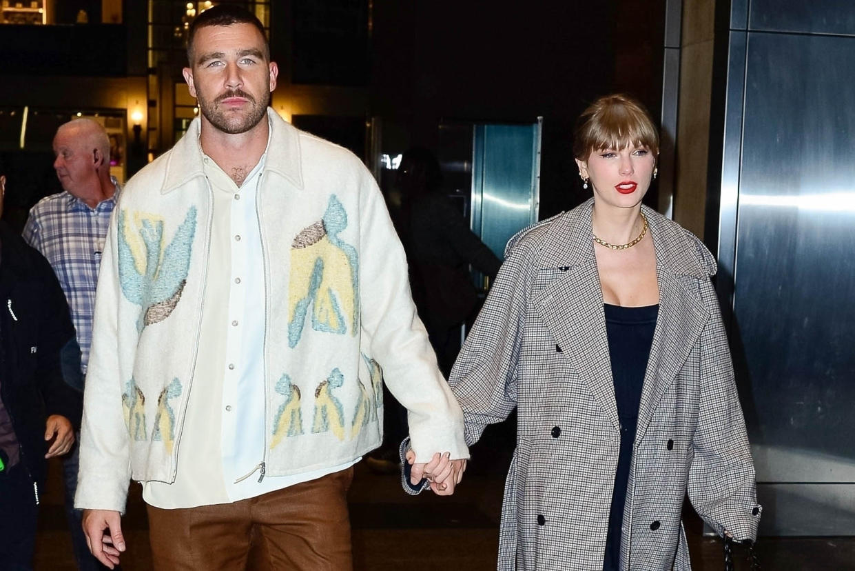 Travis Kelce and Taylor Swift holding hands while walking.