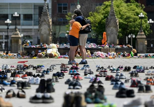 People embrace in front of the Centennial Flame on Parliament Hill June 4, 2021 at a memorial for the 215 children whose remains are believed to have been found at the grounds of the former Kamloops Indian Residential School. (Justin Tang/The Canadian Press - image credit)