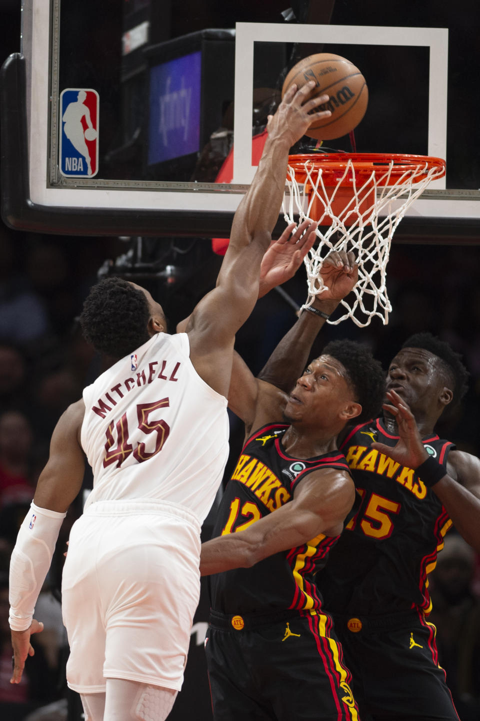 Cleveland Cavaliers guard Donovan Mitchell attempts to dunk over Atlanta Hawks forward De'Andre Hunter and center Clint Capela, right, during the first half of an NBA basketball game Tuesday, March 28, 2023, in Atlanta. (AP Photo/Hakim Wright Sr.)