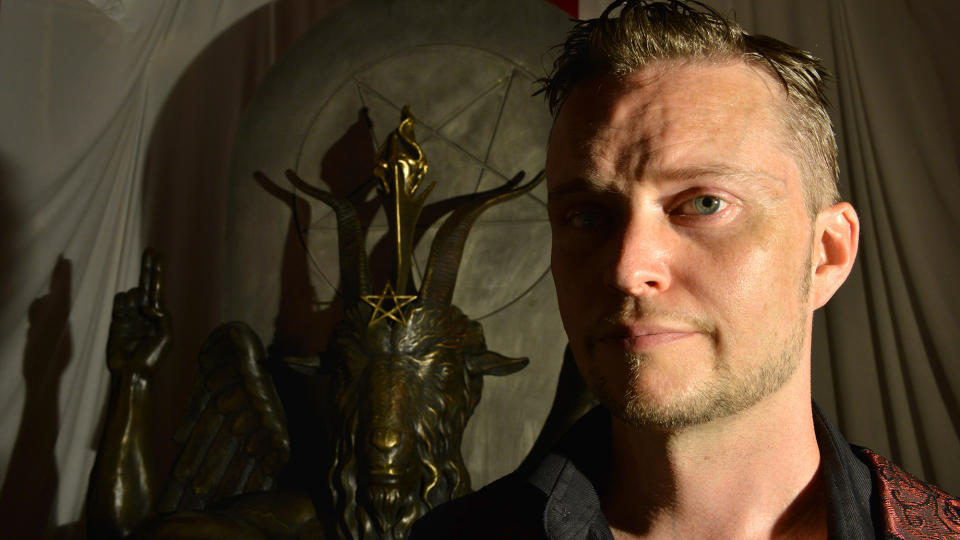 <b>Satanic Temple spokesperson Lucien Greaves stands in front of a statue of Baphomet. The church is known for its outspokenness on social and political issues.</b> The Washington Post/Getty Images