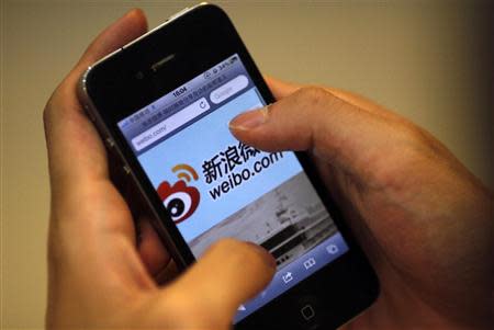 A man holds an iPhone as he visits Sina's Weibo microblogging site in Shanghai in this May 29, 2012 file photo. REUTERS/Carlos Barria/Files