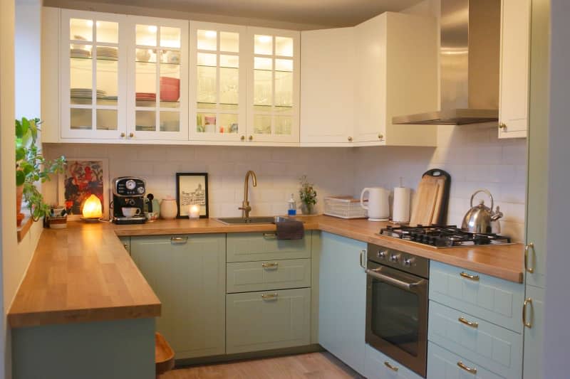 Green cabinets in kitchen with butcher block.