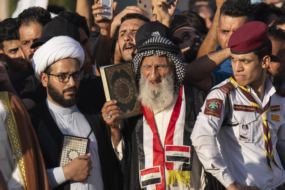 Supporters of the Shiite cleric Muqtada al-Sadr raises the Quran, the Muslims' holy book, during a demonstration in front of the Swedish embassy in Baghdad in response to the burning of Quran in Sweden, Baghdad, Iraq, Friday, June 30, 2023. (AP Photo/Hadi Mizban)