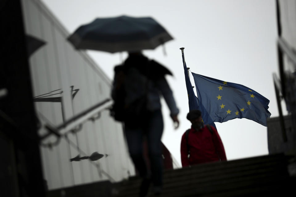 Passers-by shelter against the rain outside the EU headquarters in Brussels, Wednesday, Sept. 4, 2019. The European Union says so far it has received no proposals from the British government aimed at overcoming the impasse in Brexit talks. (AP Photo/Francisco Seco)