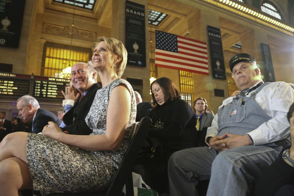 New York poet Billy Collins, second from left, Broadway star Cynthia Nixon, third from left, and retired Amtrak conductor Tom Savio, right, are among invited guests attending the Grand Central Terminal centennial celebration on Friday, Feb. 1, 2013 in New York. Grand Central, once in danger of being demolished, is celebrating its 100th birthday with speeches, a brass band and a rollback to 1913 prices when a slice of cheesecake might go for 19 cents. The majestic Beaux Arts building, known as Grand Central station although it is technically a terminal, is one of the world's most popular tourist destinations. (AP Photo/Bebeto Matthews)