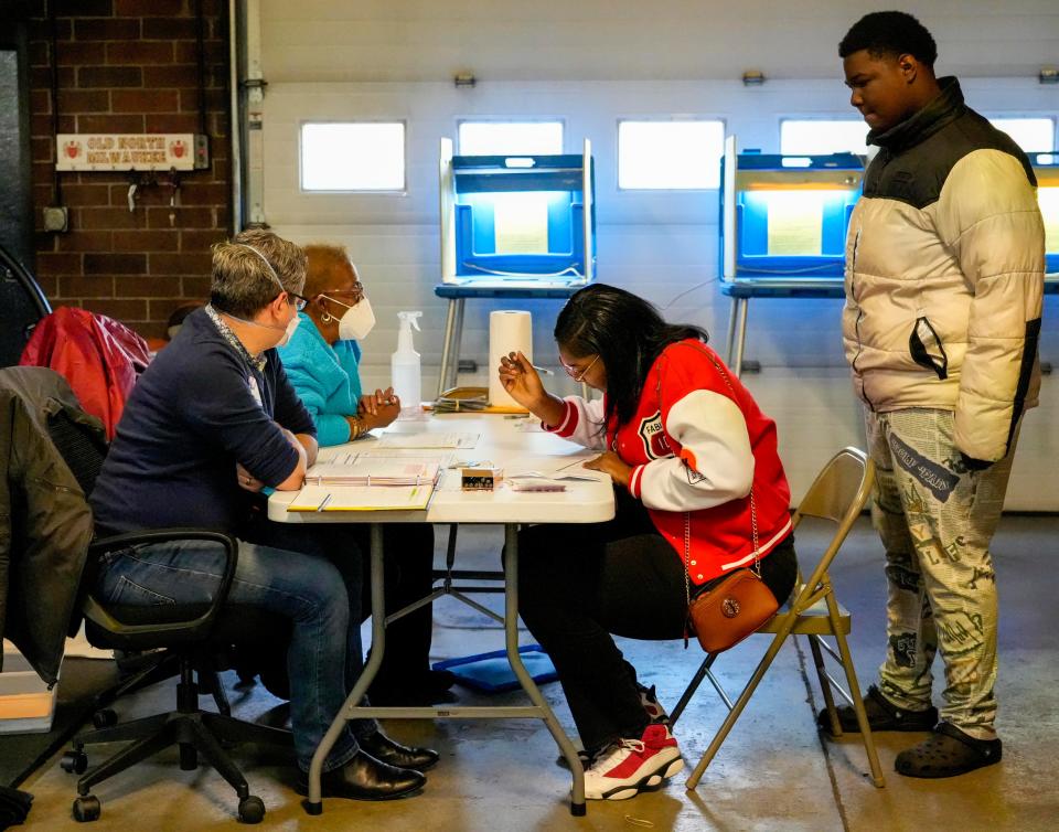 Zane Davis, from left, Linda Jackson-Howell  give Breanna Jordan paperwork to fill out for the general election while her son Jabarie Jordan waits for her Tuesday at Firehouse Station 37 located inMilwaukee. Her son J. Jordan will be able to vote in two years.