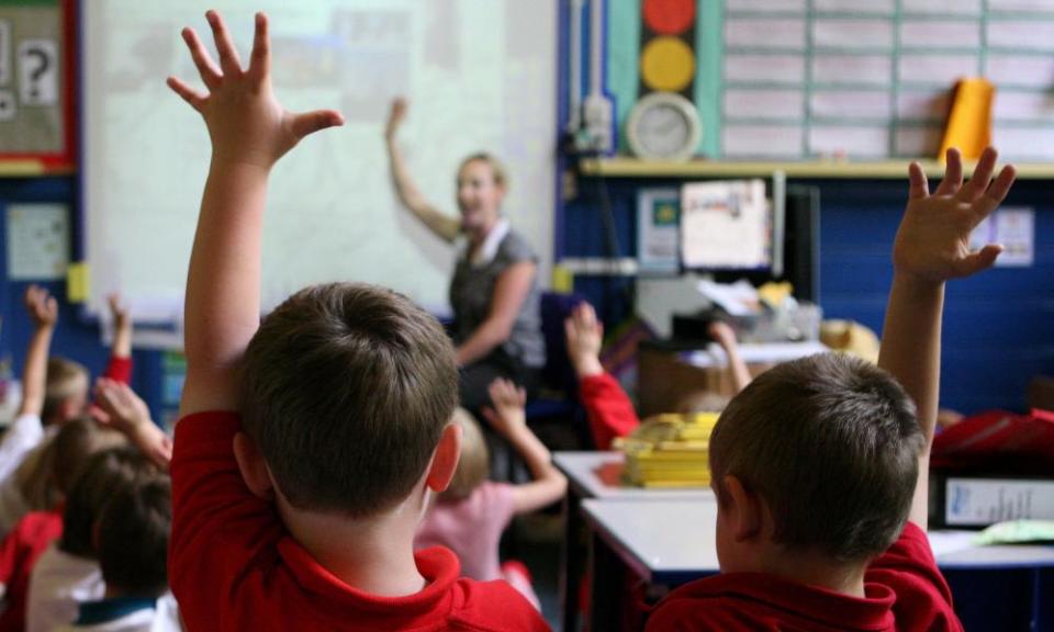 Children raise hands in class