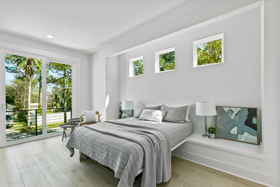 A bedroom and large window in a skinny house.