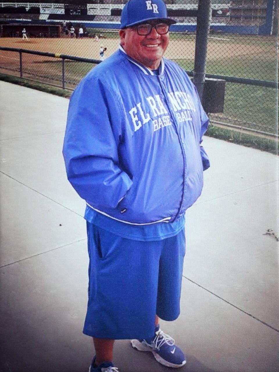 A man stands next to a baseball field.