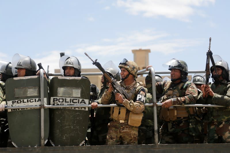 Miembros de las fuerzas de seguridad sostienen sus armas mientras partidarios del renunciado presidente boliviano Evo Morales participan en una marcha en Cochabamba