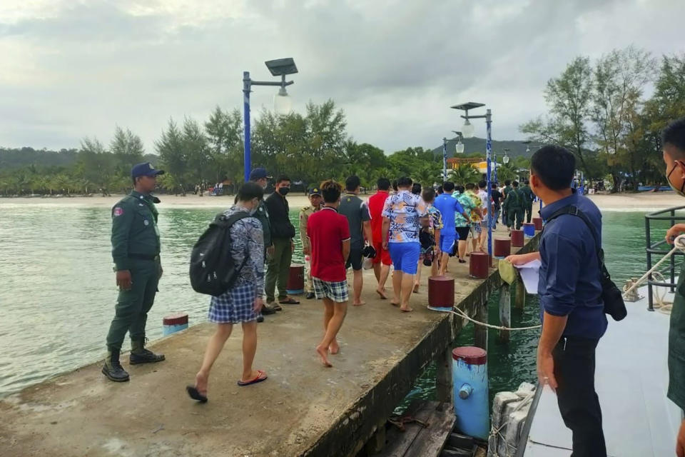 In this photo provided by the Sihanoukville Province Authority Police, Chinese nationals walk on a pier at an island in Preah Sihanouk Province, southwestern Cambodia, after they were rescued from a ship sinking, on Thursday, Sept. 22, 2022. Cambodian authorities were searching Friday, Sept. 23, for more than 20 people in the Gulf of Thailand after their boat sank near Cambodia's Koh Tang island, authorities said. (Preah Sihanouk province Authority Police via AP)