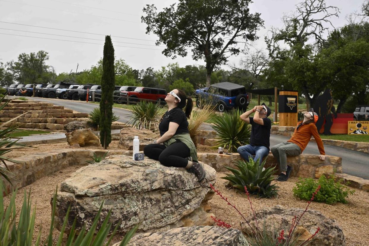 a group of people sitting on a rock in a park