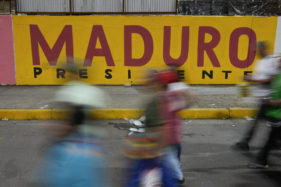 Partidarios pasan junto a un mural electoral del presidente de Venezuela, Nicolás Maduro, tras un mitin en el vecindario de Catia, en Caracas, Venezuela, el 18 de julio de 2024. Venezuela celebrará elecciones presidenciales el 28 de julio. (AP Foto/Matías Delacroix)