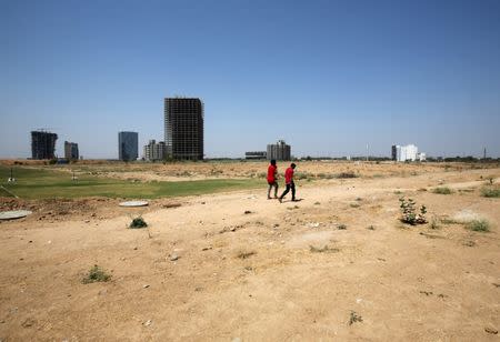 People walk past buildings under construction at the Gujarat International Finance Tec-City (GIFT) at Gandhinagar, in the western state of Gujarat, India, March 18, 2019. REUTERS/Amit Dave