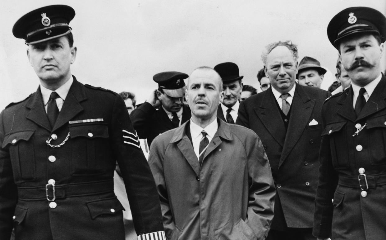 Greville Wynne is escorted by police officers on returning to Britain from the USSR in 1964 - Hulton Archive