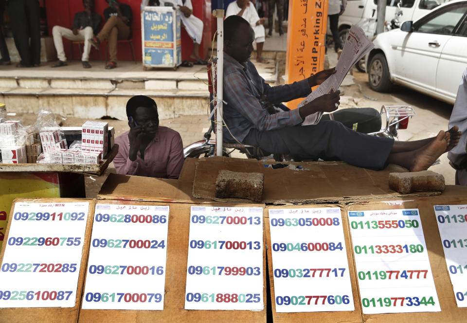 A street vendor who sells mobile sim card numbers, reads a newspaper at a popular market, in Khartoum, Sudan, Monday, June 24, 2019. (AP Photo/Hussein Malla)