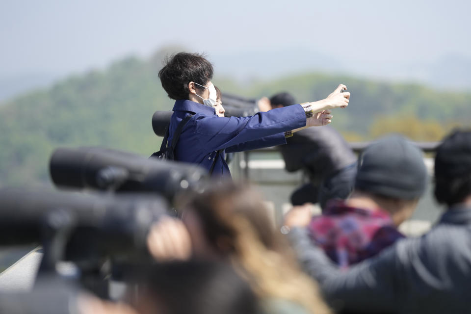 Visitors take their souvenir photo as others use binoculars to see the North Korean side from the unification observatory in Paju, South Korea, Wednesday, April 19, 2023. North Korean leader Kim Jong Un said his country has completed the development of its first military spy satellite and ordered officials to go ahead with its launch as planned, state media reported Wednesday. (AP Photo/Lee Jin-man)