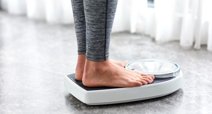 A woman is standing on a scale.  (Getty Images)