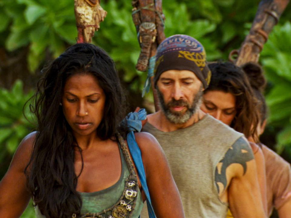 The cast of Survivor Winners at War holding torches while walking to tribal council