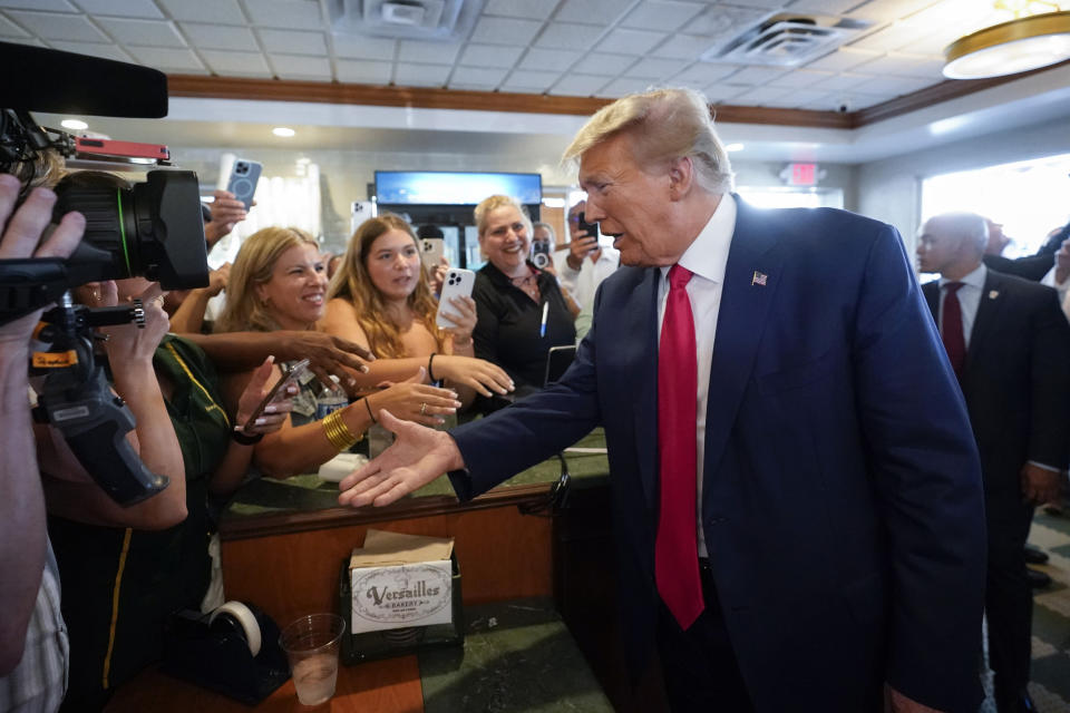 Former President Donald Trump greets supporters as he visits Versailles restaurant on Tuesday, June 13, 2023, in Miami. Trump's valet Walt Nauta, stands at right. Trump appeared in federal court Tuesday on dozens of felony charges accusing him of illegally hoarding classified documents and thwarting the Justice Department's efforts to get the records back. (AP Photo/Alex Brandon)