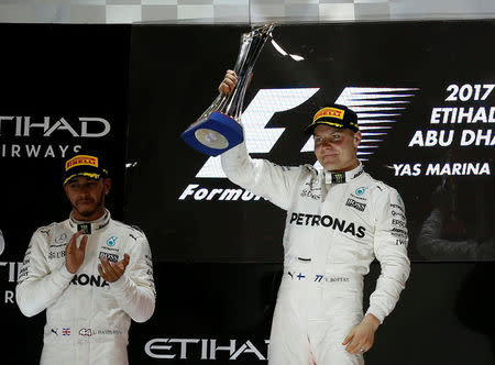 Formula One - Abu Dhabi Grand Prix - Yas Marina circuit, Abu Dhabi, United Arab Emirates - November 26, 2017 Mercedes' Lewis Hamilton applauds as Mercedes' Valtteri Bottas celebrates with the trophy after winning the race REUTERS/Ahmed Jadallah