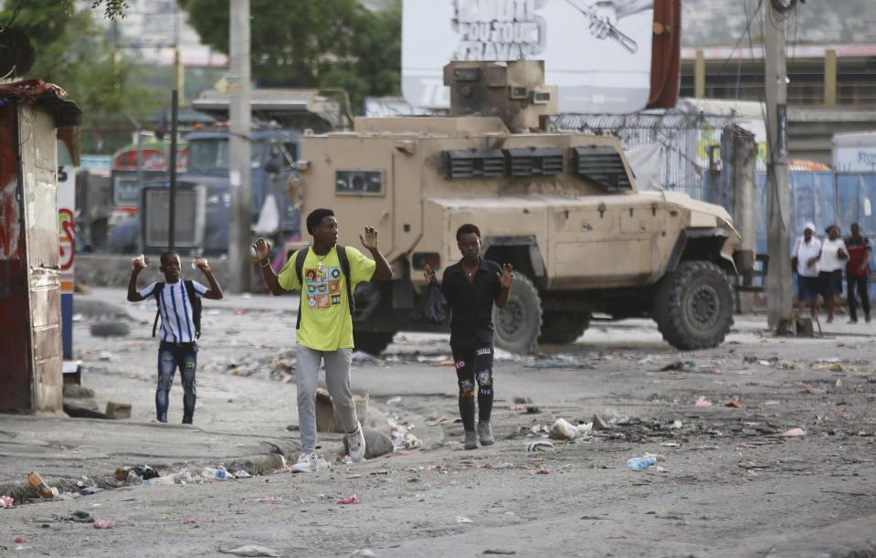 Youths raise their hands to show police they are not carrying weapons during an anti-gang operation at the Portail neighborhood in Port-au-Prince, Haiti, Thursday, Feb. 29, 2024. Gunmen shot at the international airport and other targets in a wave of violence that forced businesses, government agencies and schools to close early. (AP Photo/Odelyn Joseph)