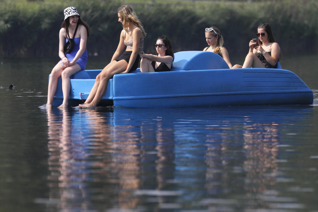 People relax in a pedal boat on The Serpentine in Hyde Park in London, Wednesday, Aug. 12, 2020. Thunderstorm warnings are still current for most of the UK on Wednesday, while high temperatures are forecast again for many parts of England. (AP Photo/Kirsty Wigglesworth)