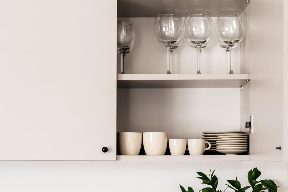 Modern white kitchen with an open cabinet for storing dishes and glasses