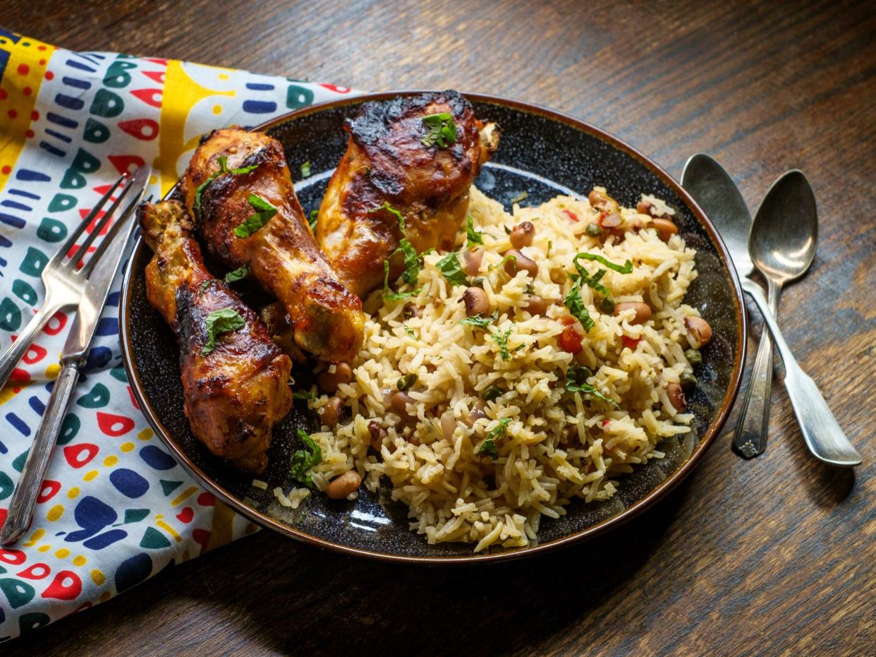 African cuisine grilled chicken legs with jollof rice with orzo and black eyed peas