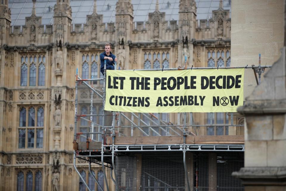 An Extinction Rebellion protester stands with a banner on the scaffolding inside the grounds of the Houses of Parliament (REUTERS)