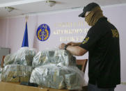 A police officer holds USD 6 million at a briefing in an anti-corruption prosecutor's office in Kyiv, Ukraine, Saturday, June 13, 2020. Ukrainian authorities say they have intercepted a $6 million bribe attempt at dropping a criminal investigation against the head of the Burisma natural gas company where former US Vice President Joe Biden's son once held a board seat. (AP Photo/Efrem Lukatsky)