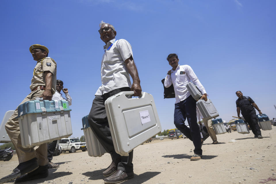 Officials carrying electronic voting machines walk to board their vehicles as they head to their assigned polling stations on the eve of the second phase of national elections at Barmer, Rajasthan, India, Thursday, April 25, 2024. (AP Photo/ Deepak Sharma)