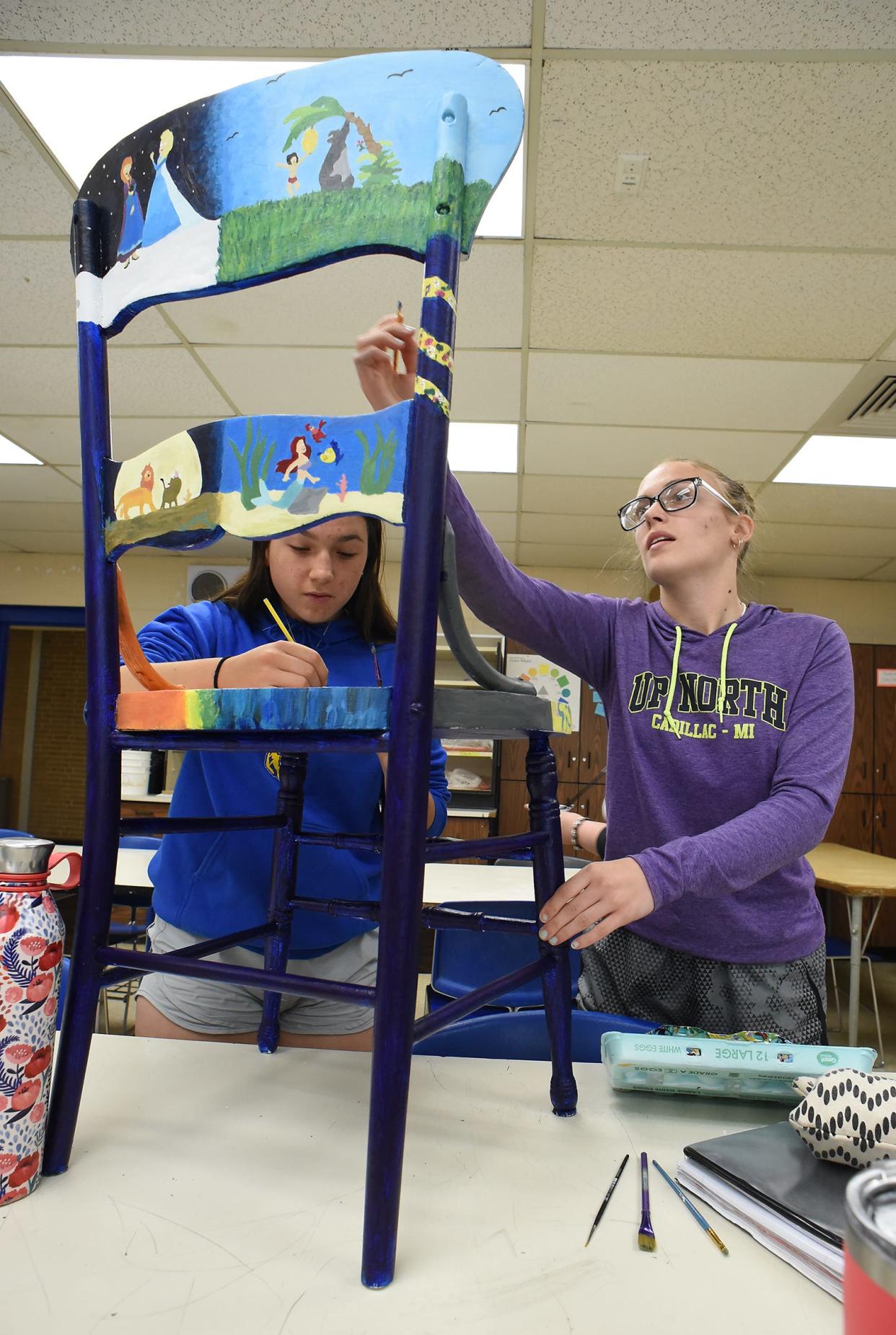 Jefferson High School sophomore Lindsey Gennoe and junior Claire Boggs work on painting a chair with a Disney theme. The chair will be featured in an auction for Relay for Life Monroe.