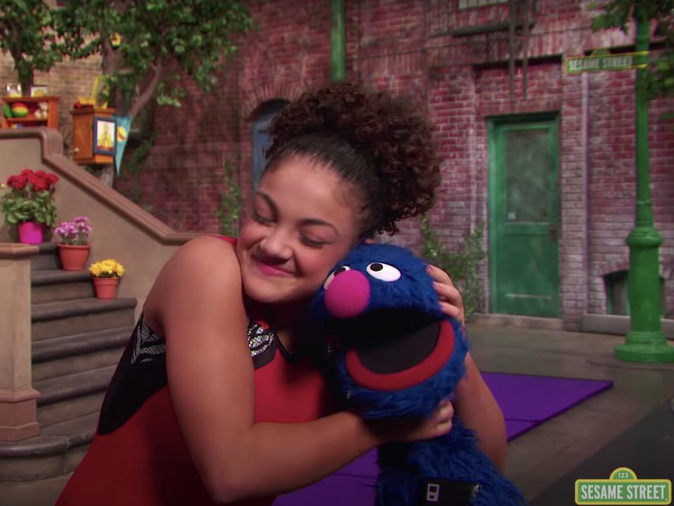 Laurie Hernandez hugs Grover during an episode of "Sesame Street."