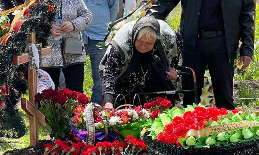 Tamara Yerchenko, 83, bends down to touch the coffin of her son Mikhayl as his remains are buried for the second time in the village of Malaya Rohan, near Kharkiv, Ukraine. Mikhayl, 60, was killed by shrapnel from a Russian tank shell, and his body was exhumed for forensic inspection by war crimes investigators. / Credit: CBS News