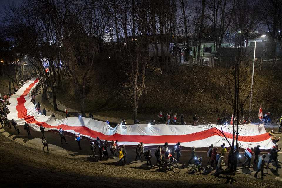 People carry a giant historical flag of Belarus during a celebration 103rd anniversary of the declaration of the Belarusian People's Respublic, in Vilnius, Lithuania, Thursday, March 25, 2021. Freedom Day is an unofficial holiday in Belarus celebrated on 25 March to commemorate the declaration of independence by the Belarusian Democratic Republic on that date in 1918.(AP Photo/Mindaugas Kulbis)