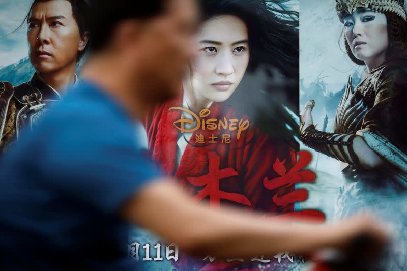 Man rides past an advertisement promoting Disney's movie "Mulan" at a bus stop in Beijing