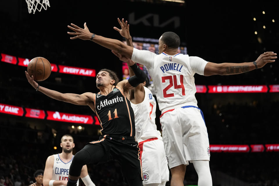 Atlanta Hawks guard Trae Young (11) goes between Los Angeles Clippers' Norman Powell (24) and Kawhi Leonard (2) to score during the second half of an NBA basketball game Saturday, Jan. 28, 2023, in Atlanta. (AP Photo/John Bazemore)