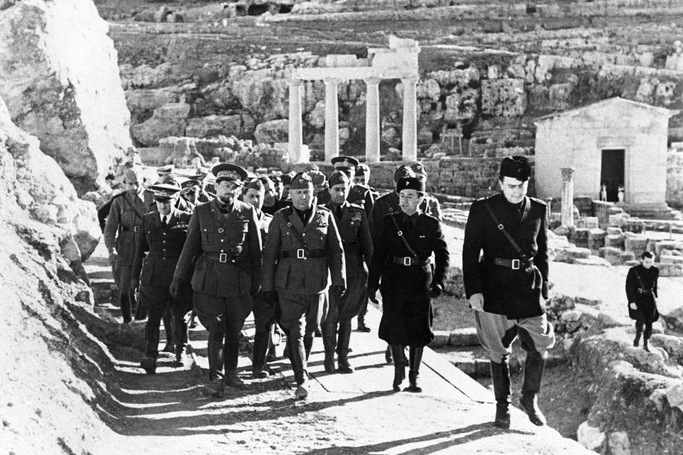 FILE - Italian dictator Benito Mussolini, center, and Marshal Italo Balbo, Governor of Libya, left, inspect the excavations of the historical remains at Cirene, Libya, March 16, 1937. Italy, a long time victim of antiquities theft that has worked for decades to recover its treasures, is coming to terms with the fact that it, too has stolen loot in its museum collections: the relics of a brutal colonial empire that the country hasn't fully reckoned with. (AP Photo, File)