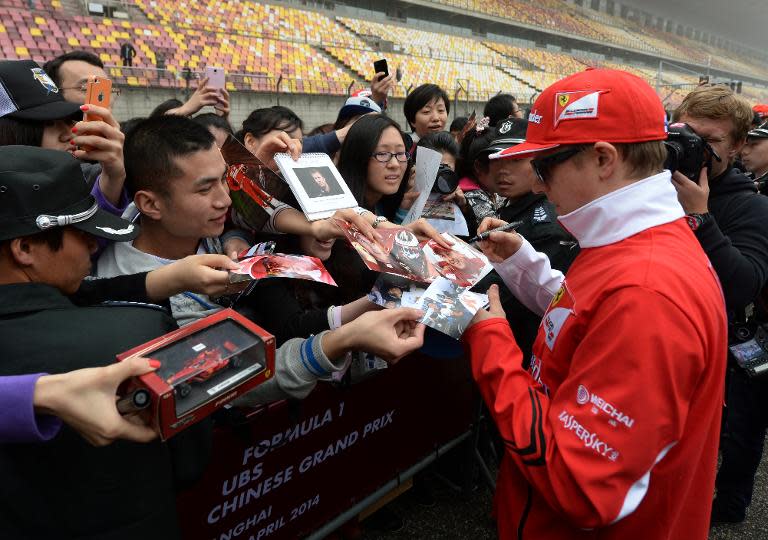 Scuderia Ferrari driver Kimi Raikkonen of Finland signs autographs for fans before the upcoming Formula One Chinese Grand Prix in Shanghai on April 17, 2014