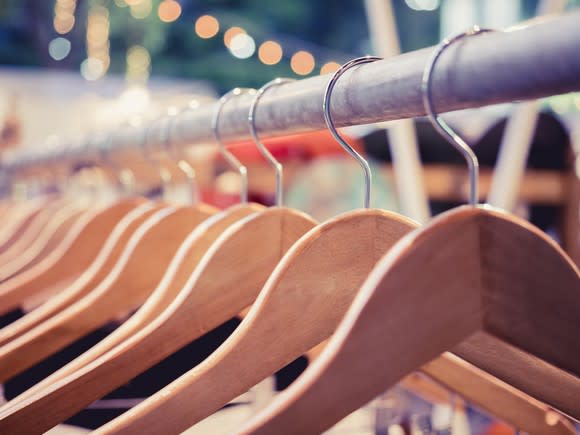 Wooden hangers on a retail fashion shopping rack.